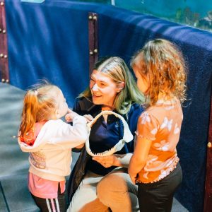 Aquarium staff showing young girls shark teeth.